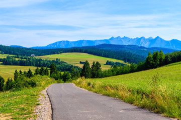 Fototapeta na wymiar Cycling road around Tatra Mountains and green fields on summer day with beautiful blue sky, Poland