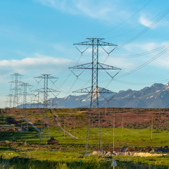 Square frame Power lines towering over neighborhood and roads in the valley on a sunny day