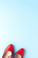 Elegant women’s shoes. Red high heels on blue background with copyspace