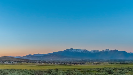 Scenic panoramic view of the valley lake and snow peaked mountain under blue sky