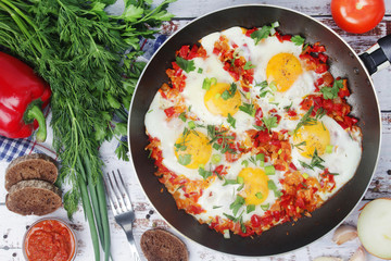 Shakshouka with five cooked eggs on top of tomato sauce in cast iron skillet