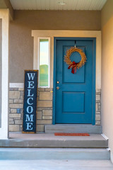 Vertical frame Golden wreath on the blue front door of a house with concrete and stone wall