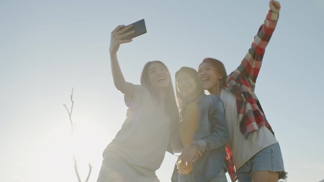 Asian teenage girl are using phone to take selfie with friend. At sunset In the midst of nature In the summer time