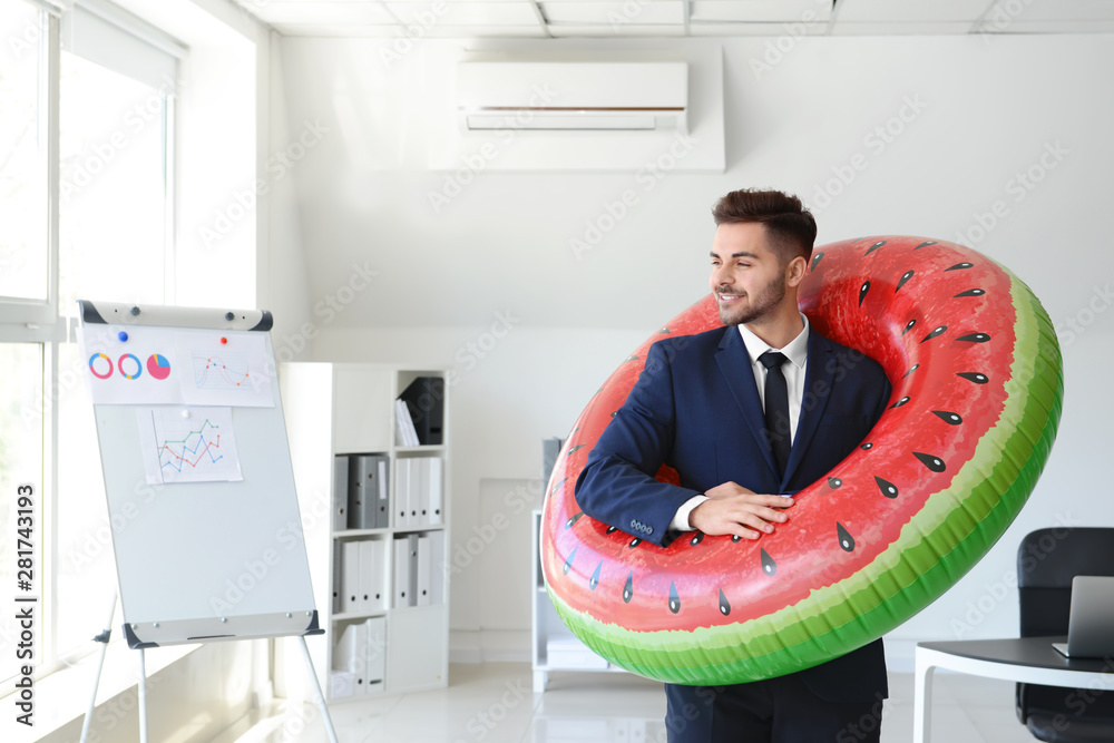 Canvas Prints Handsome businessman with inflatable ring in office. Travel concept