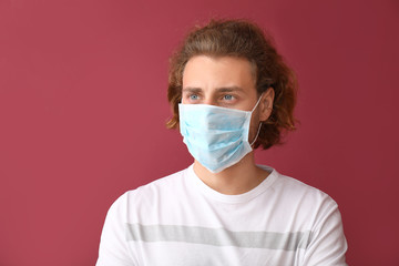 Young man wearing protective mask on color background
