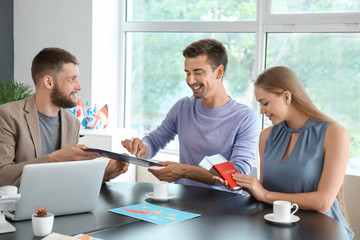 Male travel agent working with young couple in office