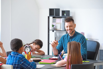 Cute children with teacher during lesson in classroom