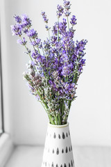 Beautiful lavender flowers in vase on window sill