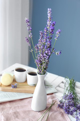 Beautiful lavender flowers in vase on table in room