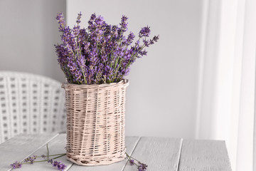 Beautiful lavender flowers in vase on table in room