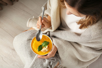 Woman eating tasty cream soup at home