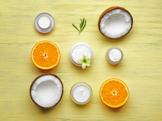 Composition with body cream, orange and coconut on wooden background