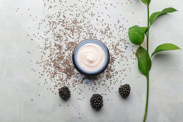 Composition with jar of natural cream, plant and blackberry on grey background