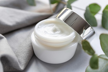 Jar of natural cream and eucalyptus branch on table