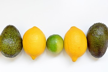 Top table with lemons, lime and avocado in a row on white background.