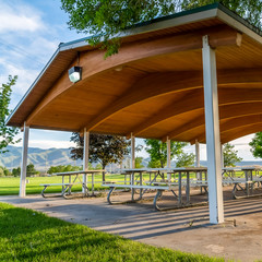 Square frame Picnic tables and benches under a pavilion on a scenic park on a sunny day