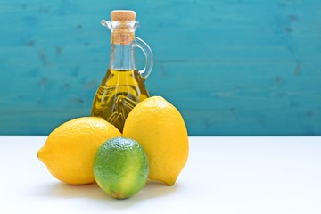 Concept of healthy food with lemons, lime and a bottle of olive oil on blue and white background. Copy text