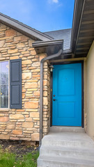 Vertical frame Home with stairs blue front door stone wall and windows with wooden shutters