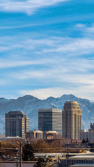 Fototapeta premium Vertical frame Building and skyscrapers on a city with snow covered mountain in the background