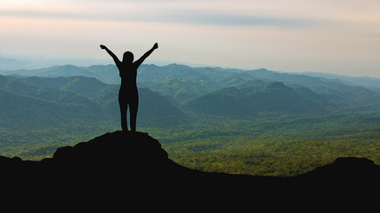 silhouette of woman on mountain top over sky and sun light background,business, success, leadership, achievement and people concept