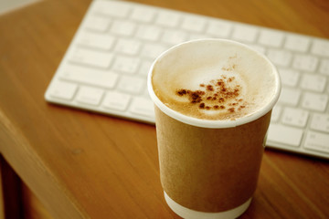 Paper coffee cup or disposable cup on the wooden table  and computer keyboard. Eco product design