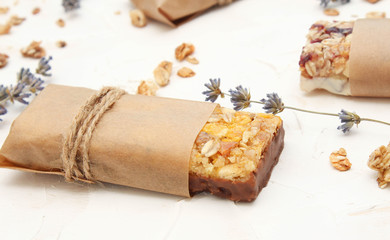 Granola bar on white table. Healthy organic sweet dessert snack. Cereal granola bar with nuts and dried fruits wrapped in  paper.