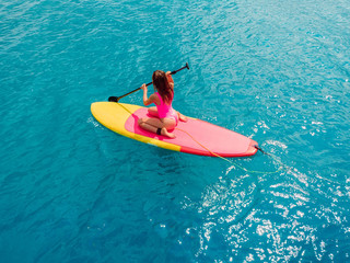 Fototapeta premium Aerial view of woman on stand up paddle board in ocean.