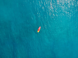 Aerial view of woman on stand up paddle board in ocean.