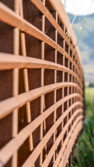 Vertical Close up of the brown metal lattice guardrail of a bridge on a sunny day