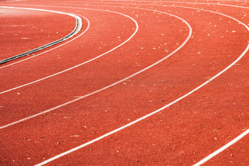 athletic red running tracks whit white lines and some leaves on it