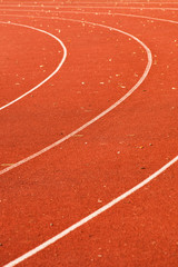 athletic red running tracks whit white lines and some leaves on it
