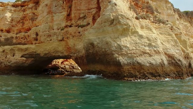 Tracking shot revealing beautiful sea caves off the coast of Portimao, The Algarve, Portugal with amazing turquoise waters