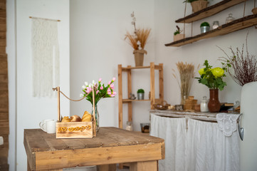 Bread in a textured wooden box in the kitchen in a rustic style. Breakfast, bread, white cups in the interior of bright Scandinavian cuisine.