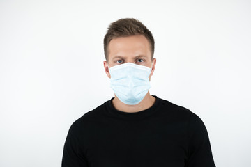 handsome young man in black t-shirt wearing medical mask on isolated white background