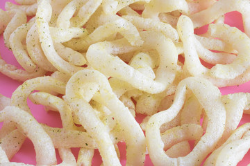 A bunch of crunchy onion rings close up on a pink background. Snack onion rings.