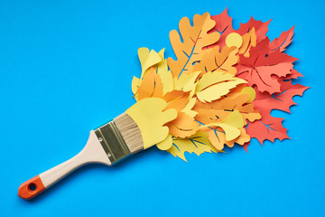 Top view of brush loaded with Autumn leaves on blue paper background