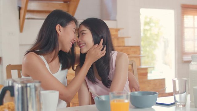 Asian Lesbian lgbtq women couple have breakfast at home, Young Asia lover girls feeling happy toothy smile looking to camera while eat cereal and milk on table in kitchen in the morning concept.
