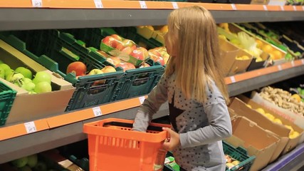 little girl at the grocery store buys apples.