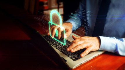 Man typing on laptop with padlock hologram screen over keyboard. Cyber security, computer protection and internet safety concept.