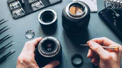 Electronic device service. Top view of man hands repairing photo camera optical dslr lens.