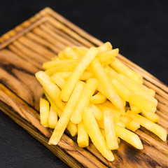 Fast food menu. Top view of traditional salted french fries on rustic wooden board.