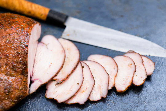 Catering service. Closeup of sliced smoked turkey breast and knife on kitchen table. Copy space.