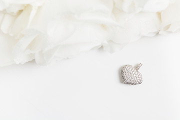 White golden pendant with diamonds and bouquet of white roses with copy space. Flat lay. Top view. Mockup