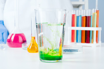 Colored liquids inside lab glassware on white table in laboratory