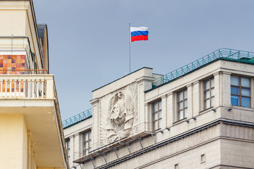 Fototapeta na wymiar Waving flag of Russian Federation on the roof of building of State Duma of Russian Federation in Moscow against blue sky