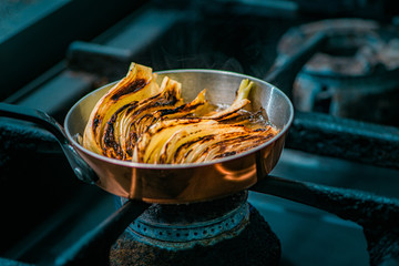 Cooking fennel bulb in a pan on a stove, close-up.