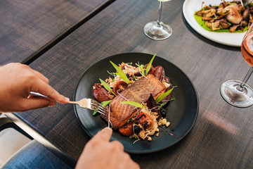 Eating juicy salmon steak with vegetables and herbs.