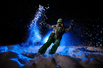 Active female snowboarder dressed in a green sportswear riding on the snow