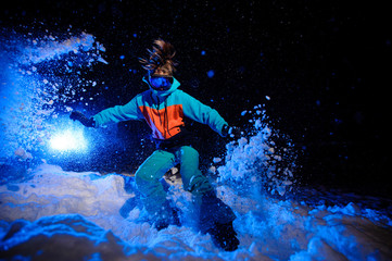 Active female snowboarder dressed in a orange and blue sportswear riding on the mountain slope