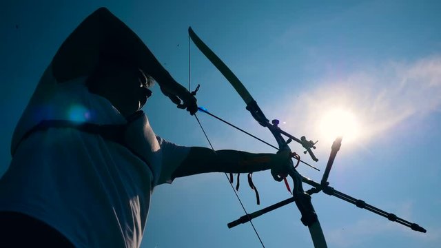 Bowman is pulling the bowstring in the sunlight. Shooting with a bow and arrows.